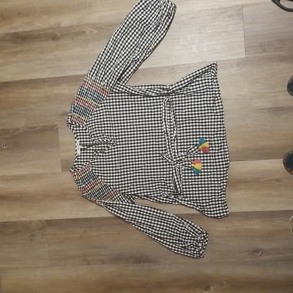 Checkered blouse with intricate details on shoulder and boho belt with pom poms
